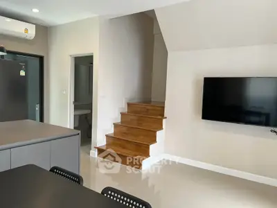 Modern interior with sleek kitchen and wooden staircase in open-plan living area.