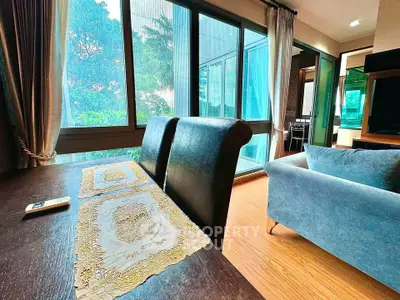 Stylish living room with large windows and elegant decor, offering a serene view and cozy ambiance.