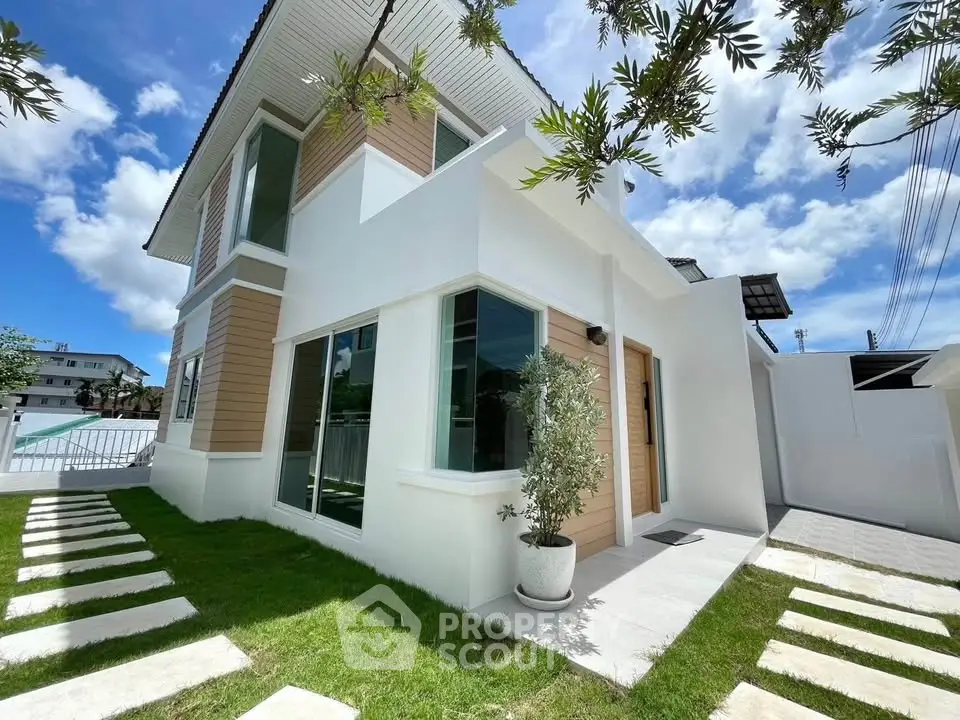Modern two-story house with sleek design and lush green lawn under a bright blue sky.