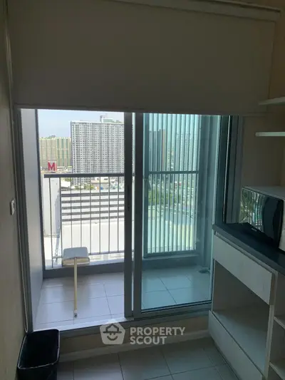 Compact balcony with city view from modern apartment, featuring sliding glass doors and minimalist decor.