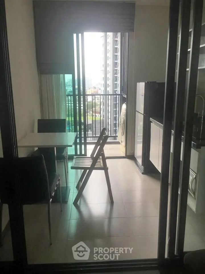 Modern apartment with balcony view and compact dining area, featuring sleek kitchen appliances.
