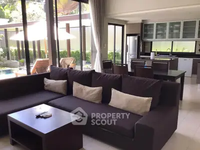 Spacious living room with modern kitchen and pool view, perfect for luxury living.