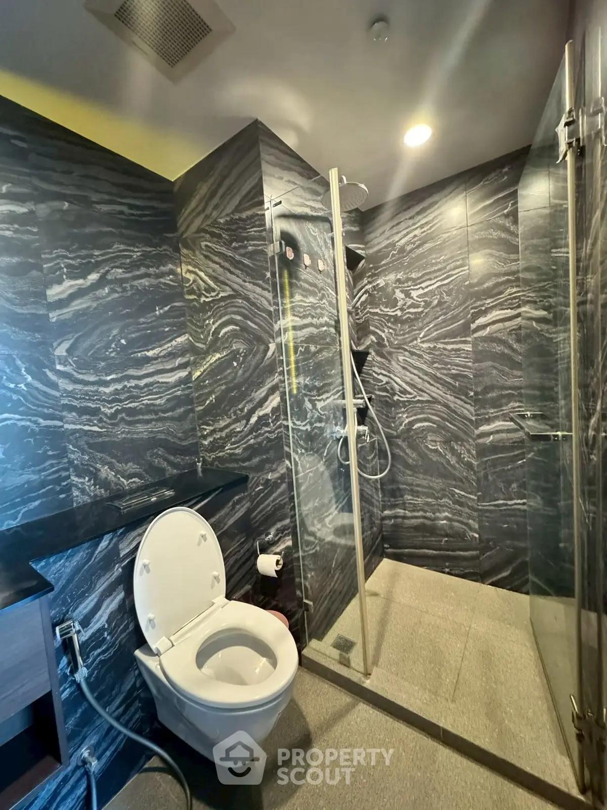 Luxurious modern bathroom with sleek marble walls and glass shower enclosure.
