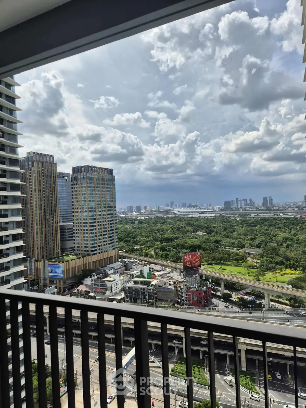 Stunning cityscape view from high-rise balcony overlooking urban skyline and lush greenery.