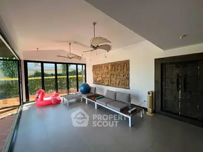 Spacious sunlit room with modern decor and large windows overlooking garden.