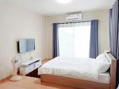 Modern bedroom with natural light, featuring a cozy bed, wall-mounted TV, and air conditioning.
