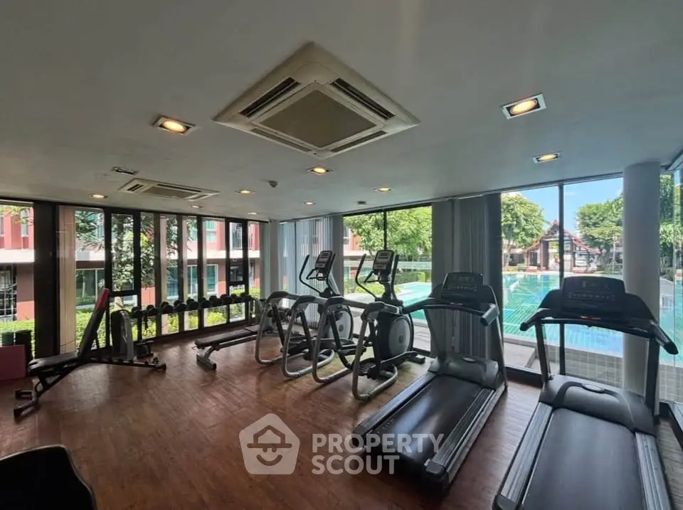 Modern gym with treadmills and pool view in luxury apartment complex