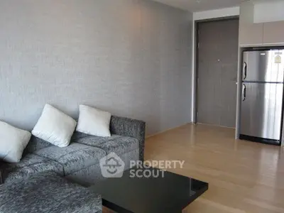 Modern living room with sleek sofa and stainless steel fridge in a stylish apartment.