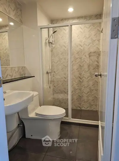 Modern bathroom with glass shower enclosure and sleek tile design.