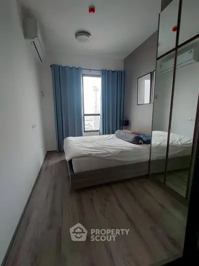 Modern bedroom with large window and mirrored wardrobe in a high-rise apartment.