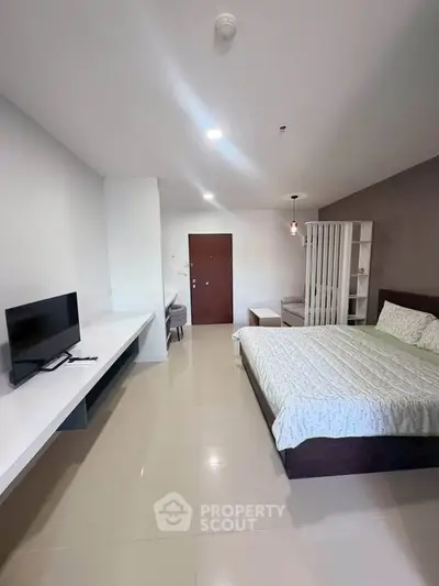 Spacious modern bedroom with TV and stylish decor in a contemporary apartment.