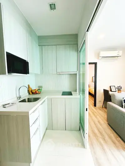 Modern kitchen with sleek cabinetry and open layout adjacent to cozy living room.