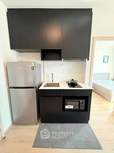 Modern compact kitchen with sleek black cabinets and stainless steel appliances