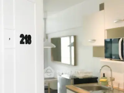 Modern kitchen interior with sleek appliances and room number 218 on the door, showcasing contemporary design.