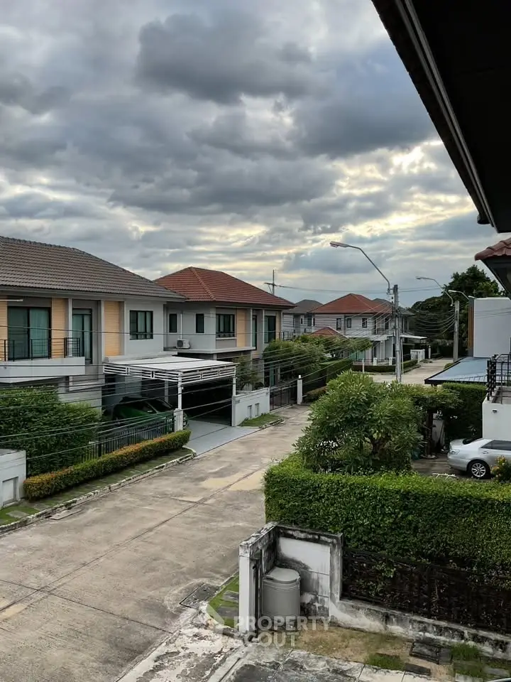 Charming suburban neighborhood with modern houses and lush greenery under a cloudy sky.