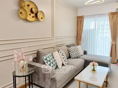 Elegant living room with modern decor and large window, featuring a stylish gray sofa and chic wall art.