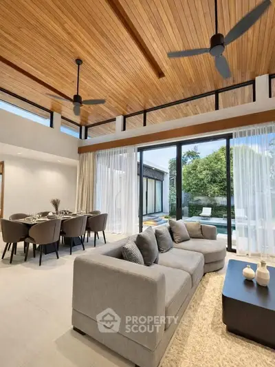Luxurious open-plan living room with elegant dining area and garden view, featuring high ceilings and modern decor.