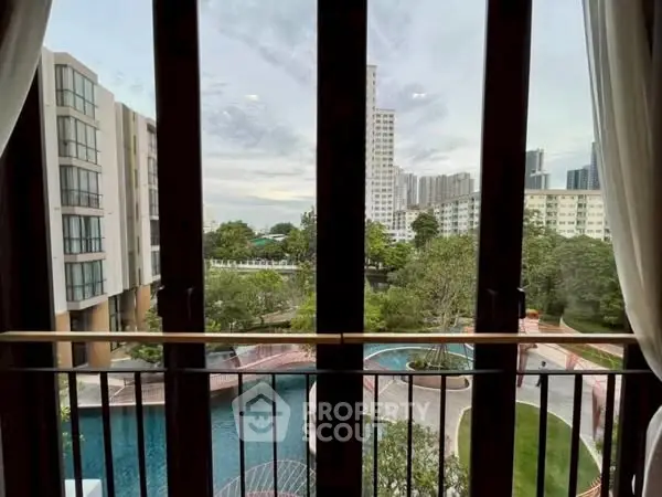 Stunning view from a high-rise apartment overlooking a serene pool and lush greenery.
