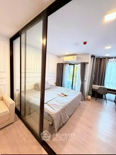 Modern bedroom with glass partition, cozy bed, and natural light from large windows.