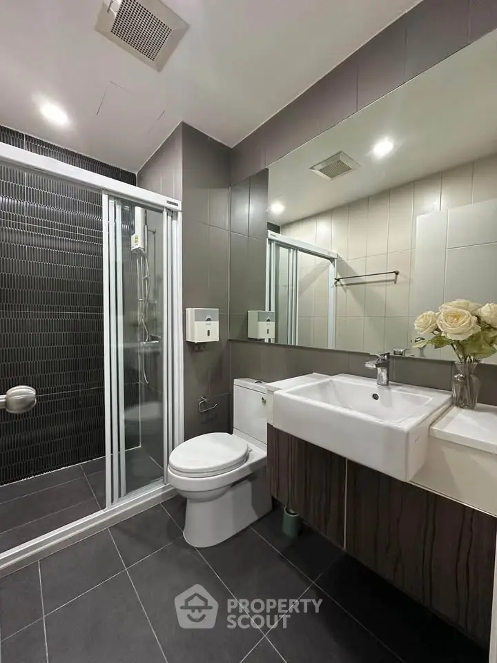 Modern bathroom with sleek design, featuring a glass shower, stylish sink, and elegant tiles.