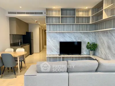 Modern living room with open kitchen, stylish shelving, and cozy seating area.
