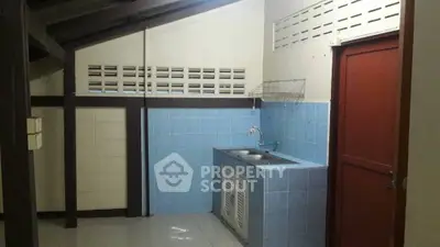 Compact kitchen space with blue tile backsplash, wooden beams, and a convenient sink area, ideal for efficient urban living.