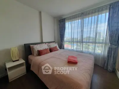 Spacious bedroom with large window offering stunning city views, perfect for relaxation and comfort.