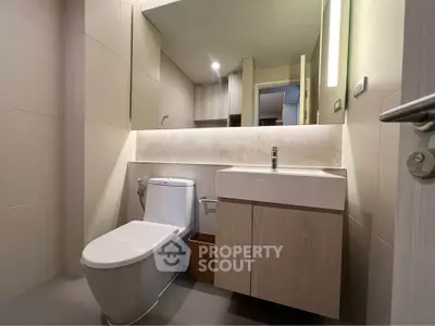 Modern bathroom with sleek fixtures and ambient lighting, featuring a stylish vanity and spacious mirror.