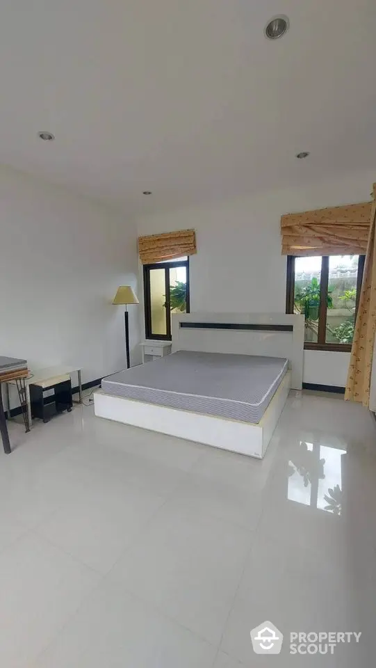 Spacious bedroom with large windows and modern furnishings in a serene setting.