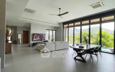 Spacious modern living room with large windows offering stunning mountain views, featuring elegant dining area and cozy seating.