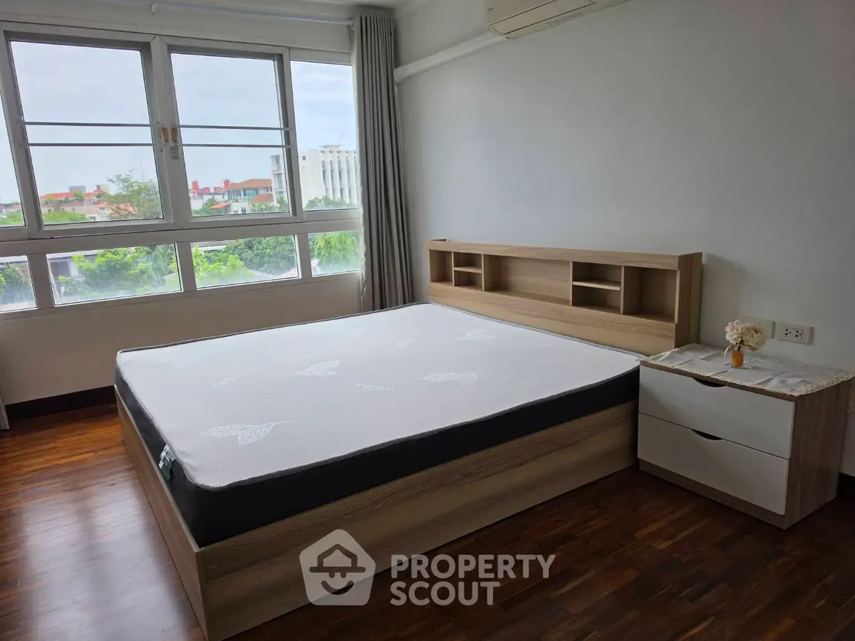 Spacious bedroom with large window and modern wooden furniture