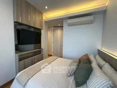 Modern bedroom with sleek design and cozy ambiance, featuring built-in storage and air conditioning.