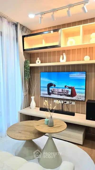 Modern living room with stylish decor and wall-mounted TV, featuring elegant lighting and wooden accents.