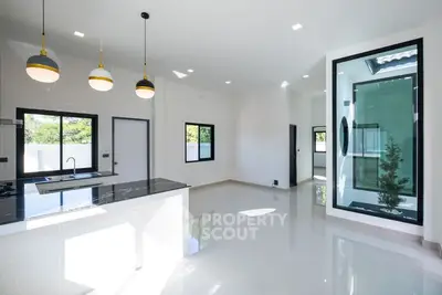 Modern open-plan kitchen with sleek black countertops and pendant lighting.