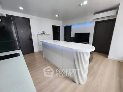 Modern living room with sleek design and ambient lighting, featuring a central island and stylish decor.