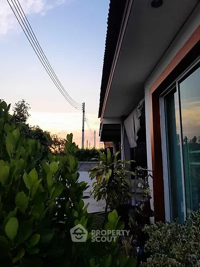 Charming suburban home exterior with lush greenery and sunset view.