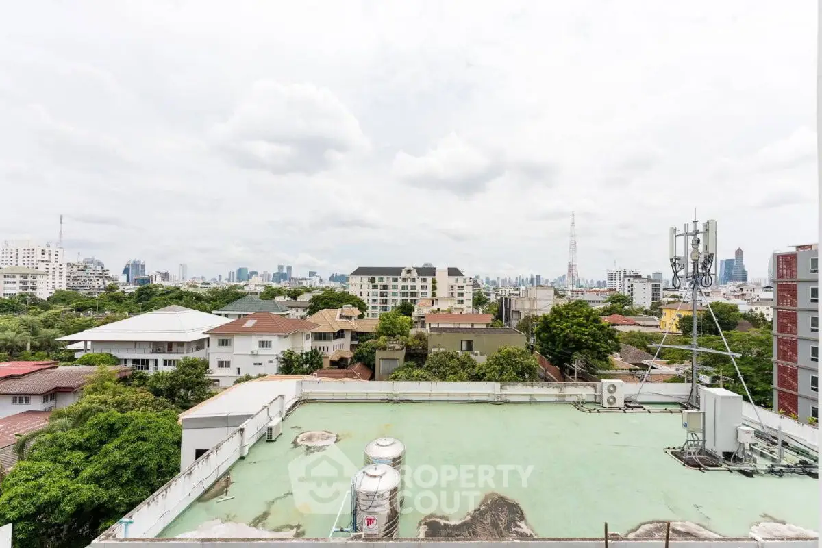 Stunning cityscape view from rooftop with lush greenery and skyline in the background.