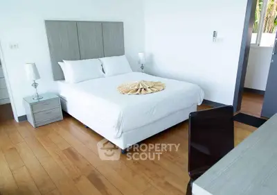 Modern bedroom with wooden flooring and stylish decor in a bright, airy space.
