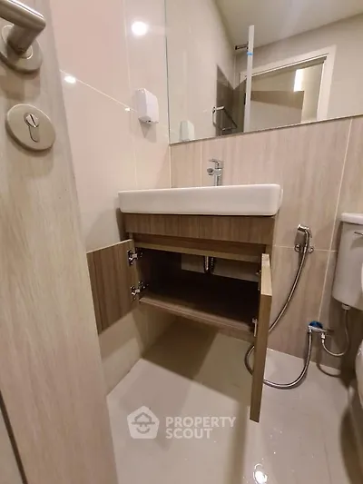 Modern bathroom with sleek sink and open cabinet showcasing plumbing details.