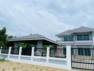 Modern two-story house with spacious driveway and gated entrance, showcasing contemporary architecture and lush surroundings.