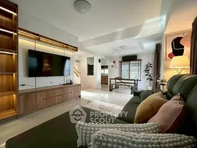 Spacious modern living room with sleek furniture and large TV, perfect for relaxation and entertainment.