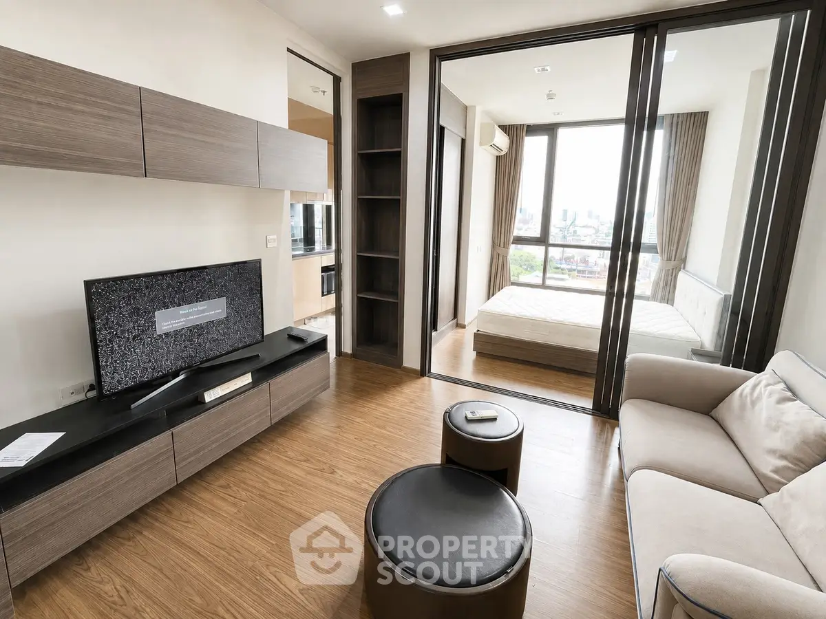 Modern apartment living room with wooden flooring and glass partition to bedroom