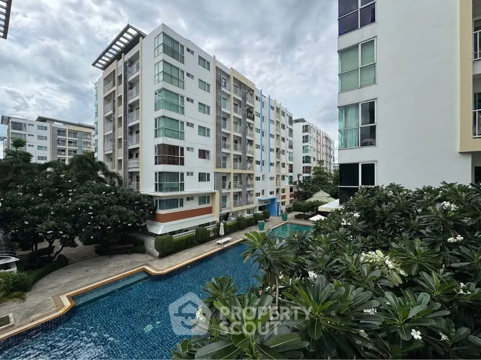 Modern condominium complex with pool and lush greenery, offering a serene urban living experience.