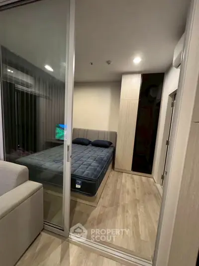 Modern compact bedroom with sliding glass doors and cozy furnishings.