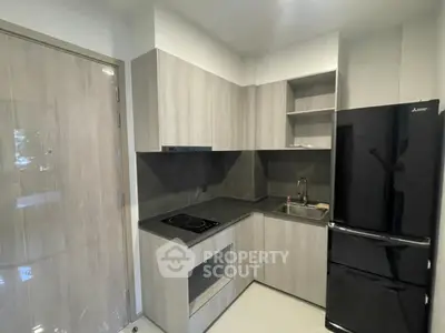 Modern kitchen with sleek black fridge and electric stove in compact layout