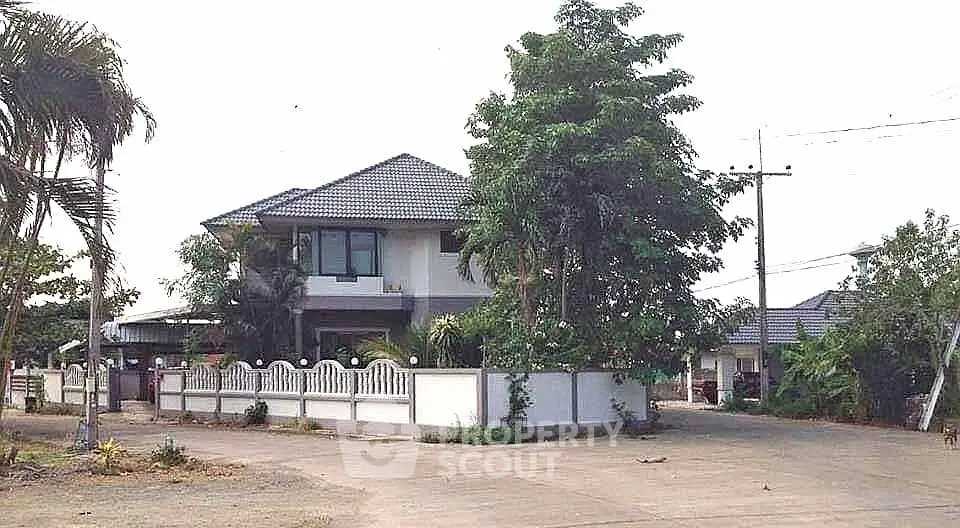 Charming two-story house with lush greenery and spacious driveway in a serene neighborhood.