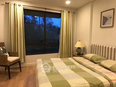 Cozy bedroom with large window and stylish decor, perfect for relaxation and comfort.