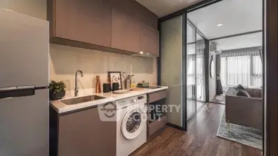 Modern kitchen with washing machine and open layout leading to stylish living room.