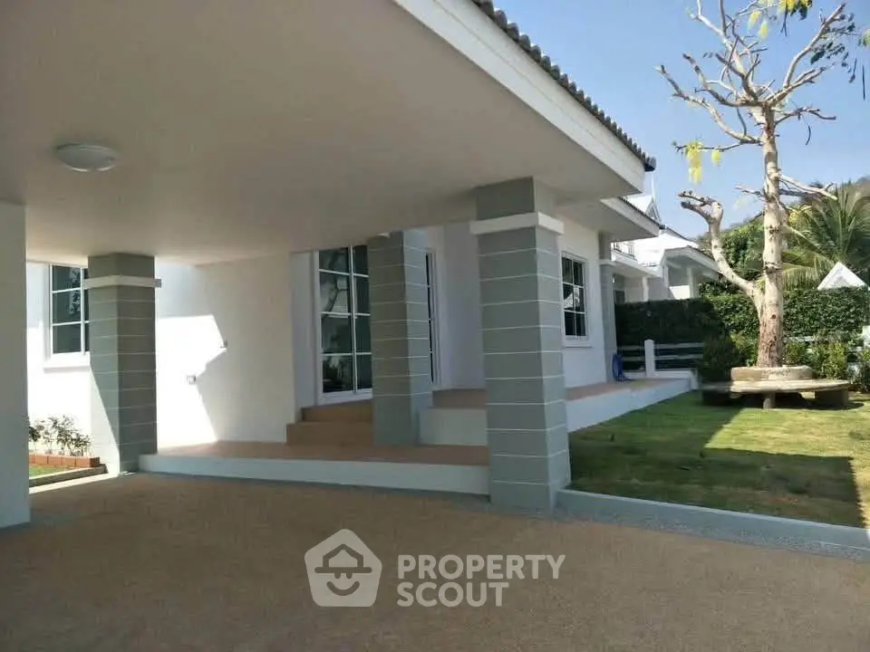 Charming modern house with spacious covered patio and lush garden, perfect for outdoor relaxation.