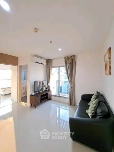 Modern living room with sleek design and natural light, featuring a comfortable sofa and TV setup.